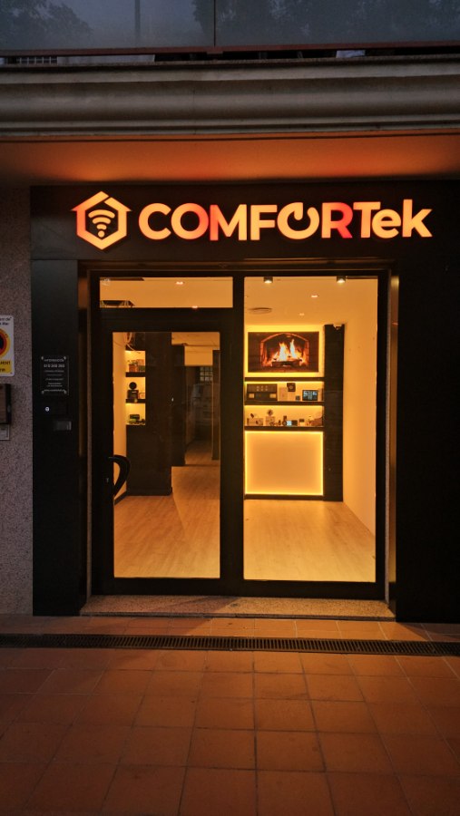 Fachada de Comfortek en Lloret de Mar, de noche: rótulo y escaparate iluminados